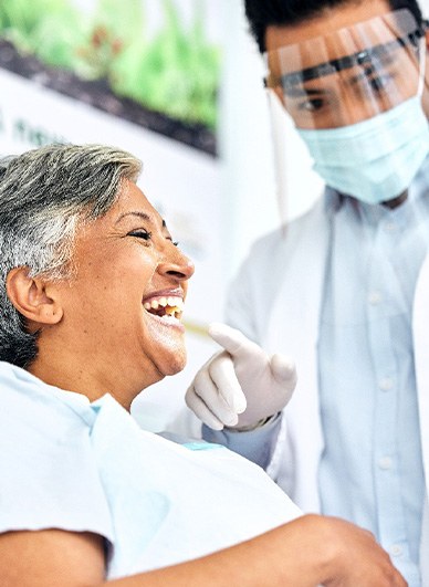 Patient smiling at reflection in mirror with dentist