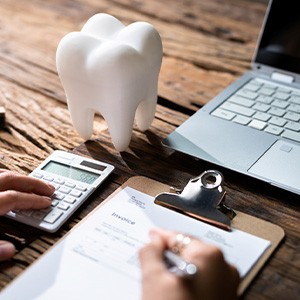 Patient filling out paperwork on desk with laptop