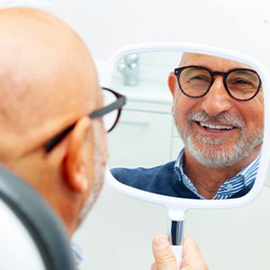 A man looking at his smile in the mirror