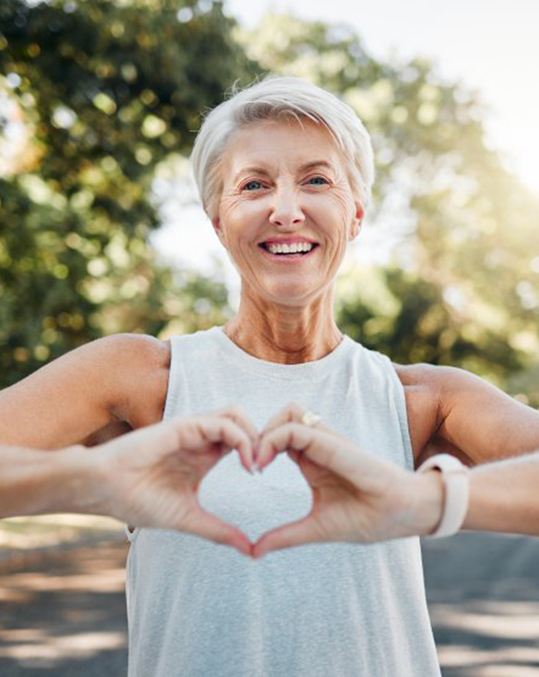 Smiling lady makes shape of heart with her hands
