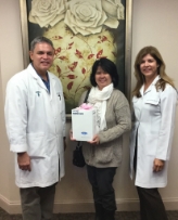 Two dentists smiling with a patient holding a box