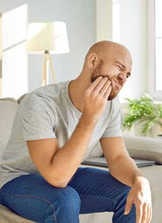 Man rubbing jaw looking uncomfortable