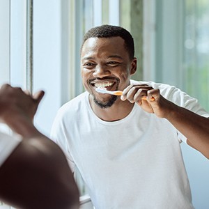 Smiling dentist showing patient model of teeth