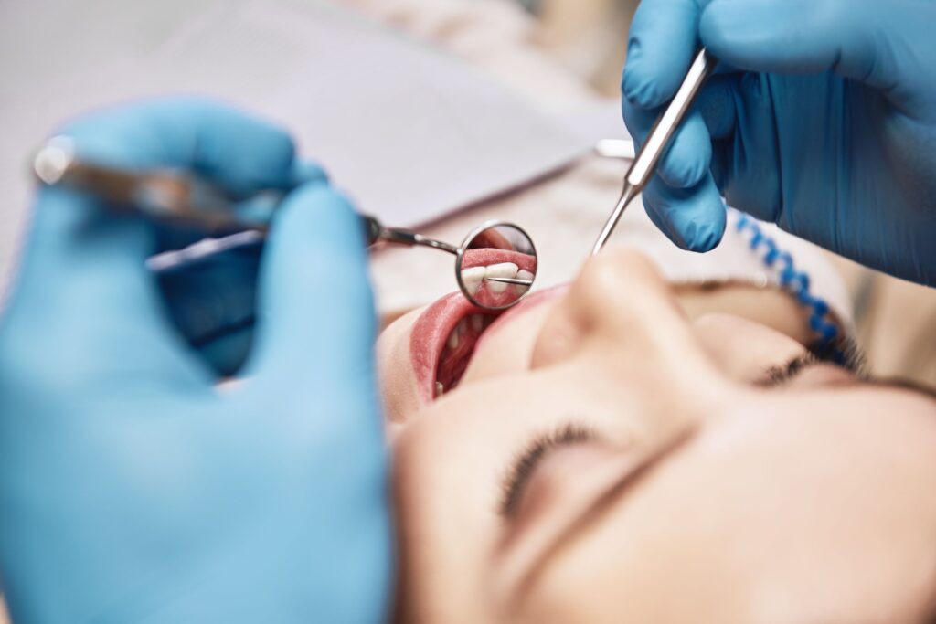 Closeup of dentist's blue-gloved hands examining woman's mouth