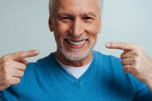 Older man smiling and showing off dentures.