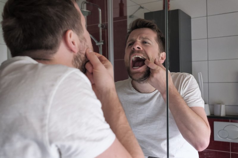 Patient checking dental implants in mirror 