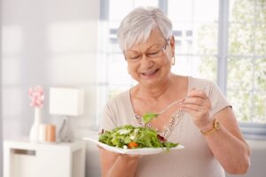 woman wearing dentures and preparing to eat a salad
